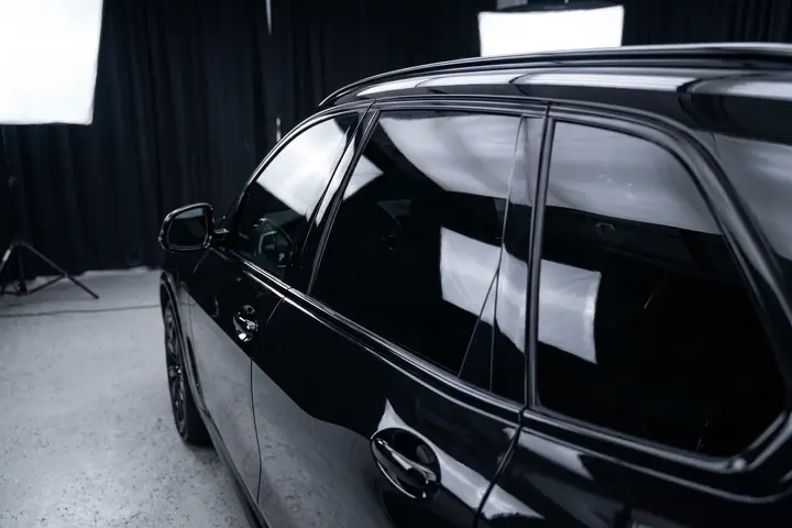 BMW X5 preto num estúdio, com os vidros escurecidos por igual e o interior escondido