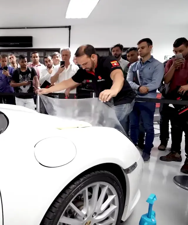 Demonstração de aplicação de PPF num Porsche branco para uma plateia de profissionais