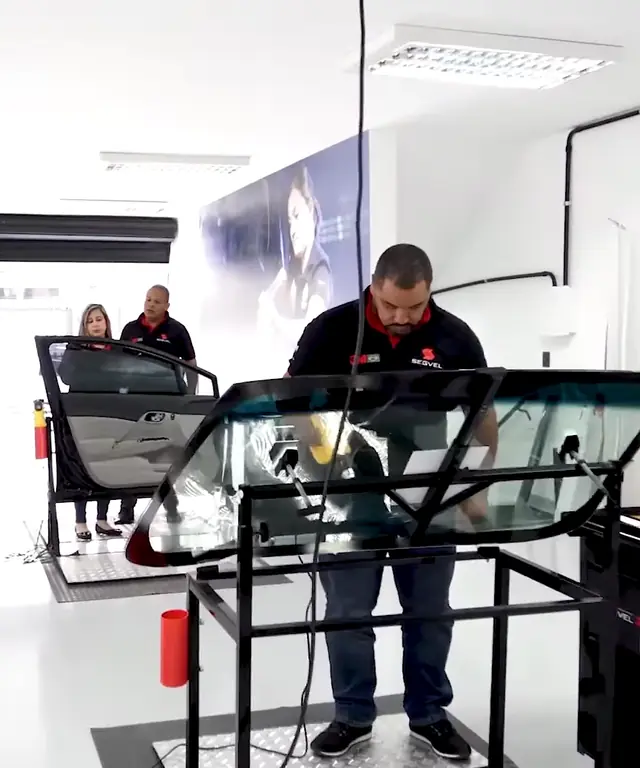 Instrutor aplicando película em um para-brisa numa das estações do centro de treinamento